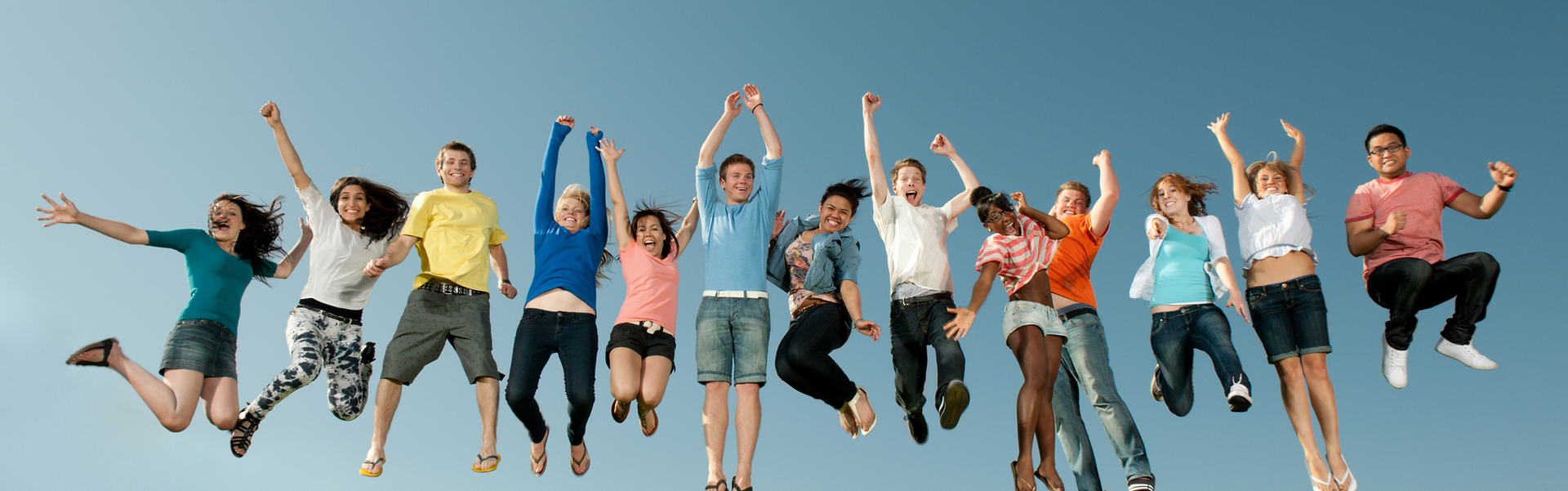 Diverse group of people jumping joyfully against a blue sky